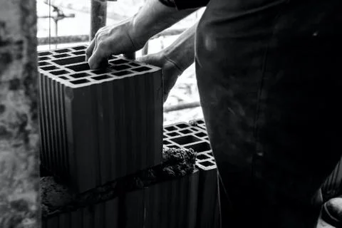 Worker is building wall with red blocks and mortar Fotos de archivo