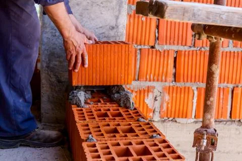 Worker is building wall with red blocks and mortar Fotos de archivo