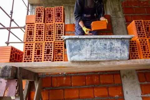 Worker is building wall with red blocks and mortar Stock Photos