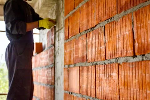 Worker is building wall with red blocks and mortar Fotos de archivo