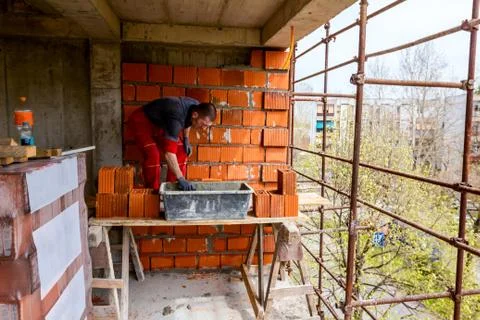 Worker is building wall with red blocks and mortar Stock Photos