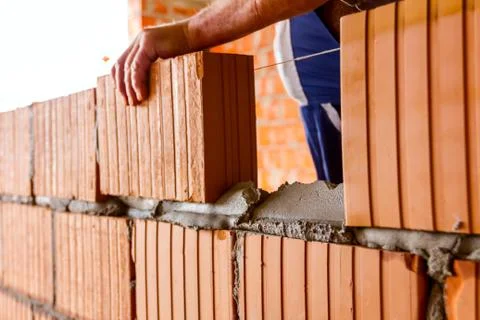 Worker is building wall with red blocks and mortar Stock Photos