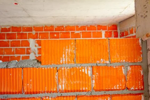 Worker is building wall with red blocks and mortar Fotos de archivo