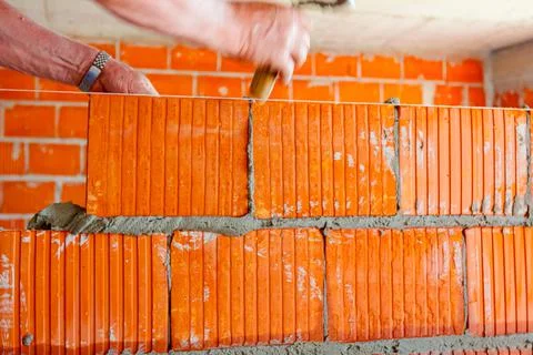 Worker is building wall with red blocks and mortar Fotos de archivo