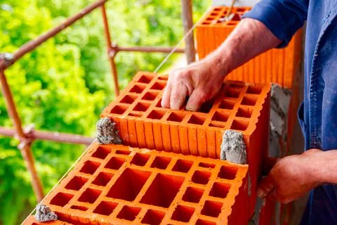Worker is building wall with red blocks and mortar Fotos de archivo