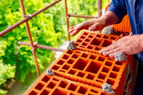 Worker is building wall with red blocks and mortar Stock Photos