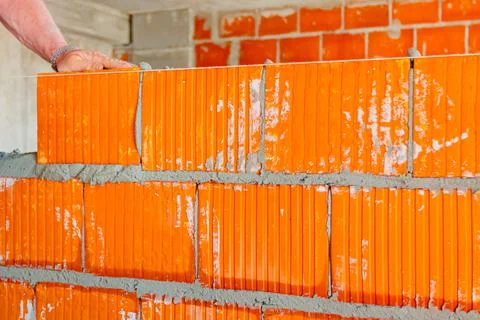 Worker is building wall with red blocks and mortar Fotos de archivo