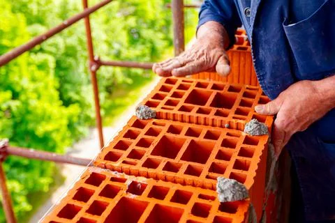 Worker is building wall with red blocks and mortar Fotos de archivo