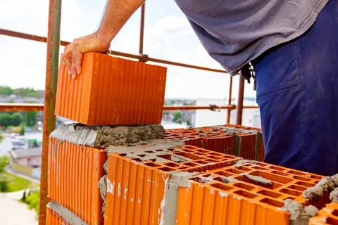 Worker is building wall with red blocks and mortar Fotos de archivo