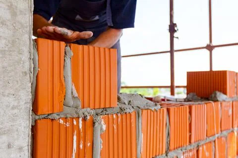 Worker is building wall with red blocks and mortar Fotos de archivo
