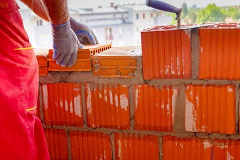 Worker is building wall with red blocks and mortar Fotos de archivo