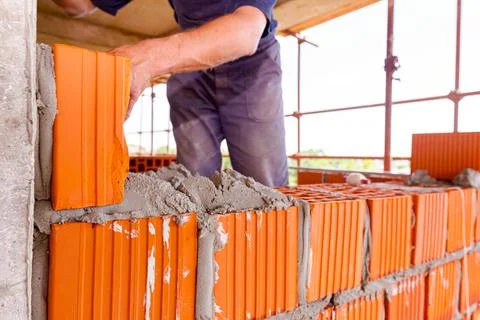 Worker is building wall with red blocks and mortar Fotos de archivo