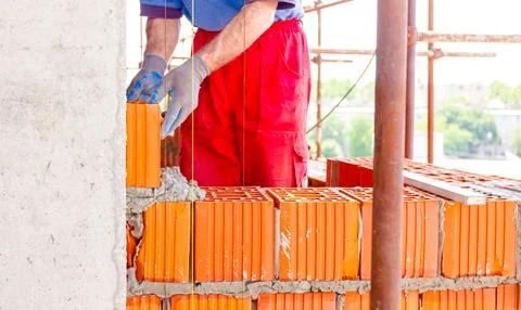 Worker is building wall with red blocks and mortar Fotos de archivo