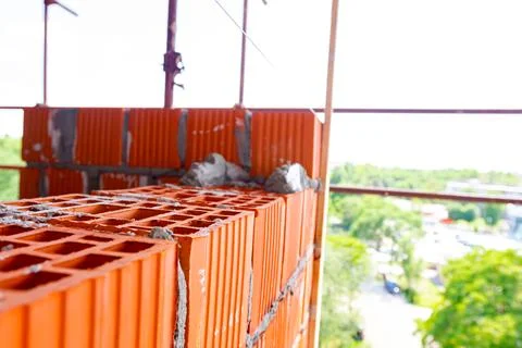 Worker is building wall with red blocks and mortar Stock Photos