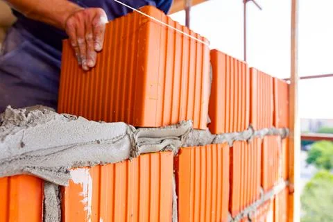 Worker is building wall with red blocks and mortar Stock Photos