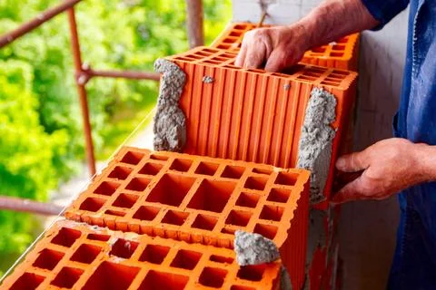  Worker is building wall with red blocks and mortar Mason, bricklayer work... Fotos de archivo