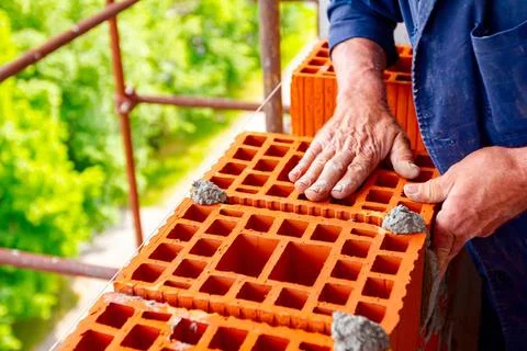 Worker is building wall with red blocks and mortar Mason, bricklayer worke... Fotos de archivo