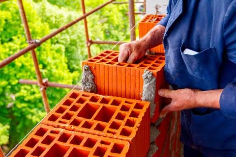 Worker is building wall with red blocks and mortar Mason, bricklayer worke... Fotos de archivo
