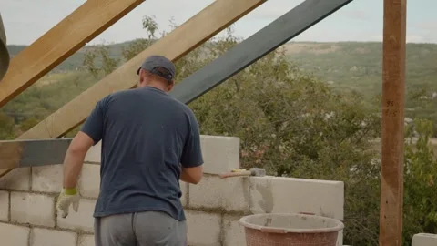 Worker builds a concrete brick wall with a trowel in a scenic location Video stock 324669778