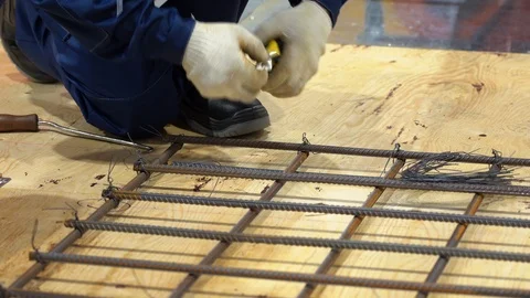 Worker builds frame from pieces of chopped rebar, tying together with thin wire Stock Footage 126357146