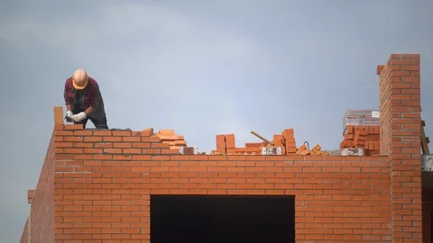 Worker builds wall of bricks. builder on building making bricklaying. builder at Stock Footage 99896993