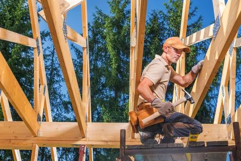 Worker builds wooden structure in construction project during daylight hours Stock Photos