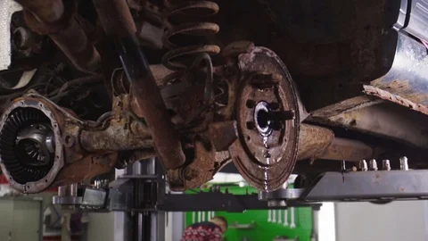Worker of car-service is checking backlash in the suspension of automobile, he Stock Footage 104831997