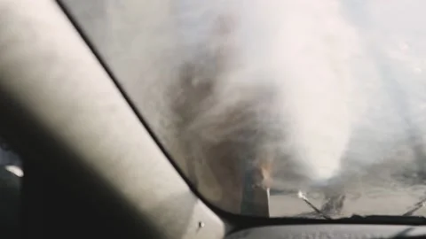 Worker in car washing shop throwing soap on car window. View from inside the car Stock-Footage 131132710