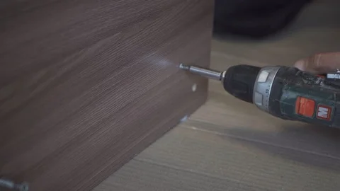 A worker carefully assembles a chipboard table close-up Stock Footage 108465131