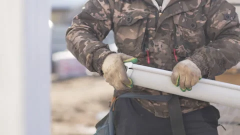 Worker carefully assembles drainage pipe structure on site Stockbeeldmateriaal 306418425