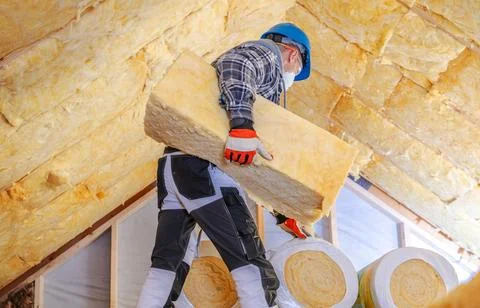 Worker carries insulation material in a construction site during the day Stock Photos