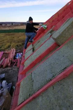 The worker carries out work on warming of the house with mineral wool. 스톡 사진