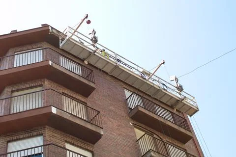 Worker carrying out work at height to rehabilitate the facade of a building Foto stock