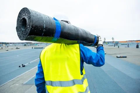 Worker Carrying Roofing Material on Flat Rooftop Under Construction Stock-Fotos