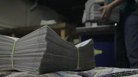 Worker carrying stack of newspaper in a Printing Press Factory Stock Footage 133879818