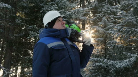 Worker with chainsaw on shoulder looking up in winter forest Stock Footage 86929516