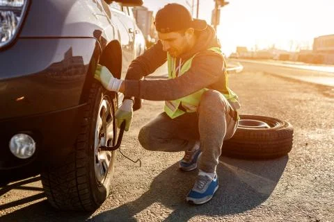 Worker changes a broken wheel of a car. The driver should replace the old wheel Stock Photos