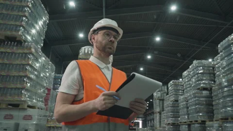 Worker checking the amount of items stocked inside of a factory warehouse Stock Footage 241397347