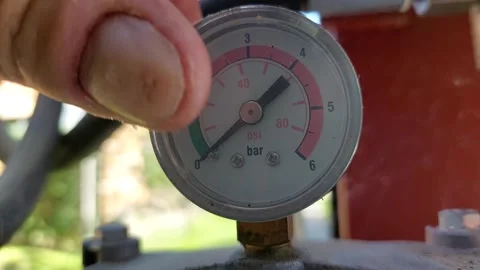 Worker checking an industrial pressure gauge manometer showing bar and psi 库存影片 336007117