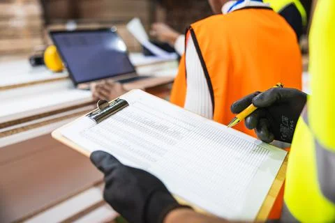 Worker checking inventory list at lumberyard Stockfoto's