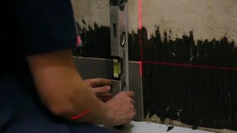 Worker checking level laying tiles on the wall Video stock 128410736