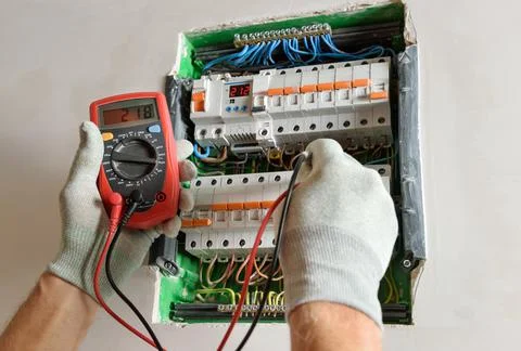 A worker is checking with a multimeter the correctness of the connection of t Stock Photos