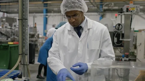Worker checking packed cosmetic boxes on conveyor belt in factory Stock Footage 107959335