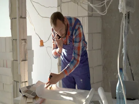 Worker checking project and speaking on cellphone, steadycam shot Stock Footage 76492706