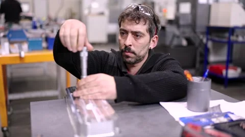Worker checking the size of holes on a metal piece Stock Footage 258706652