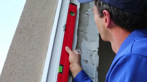 Worker checks accuracy of window frame installation with level. Video stock 50282438