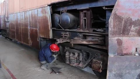 A worker checks the condition of the wheelset of an old railway locomotive. Stock Footage 124576474