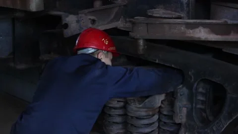 A worker checks the condition of the wheelset of an old railway locomotive. Stock Footage 124576476