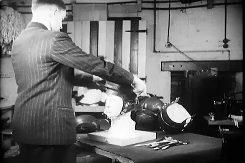 Worker checks the fitting of helmet on the dummy model - 1945 Stock Footage 99786863