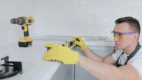 Worker checks the leveling of the working surface of the kitchen using waterpas Stock Footage 130452499